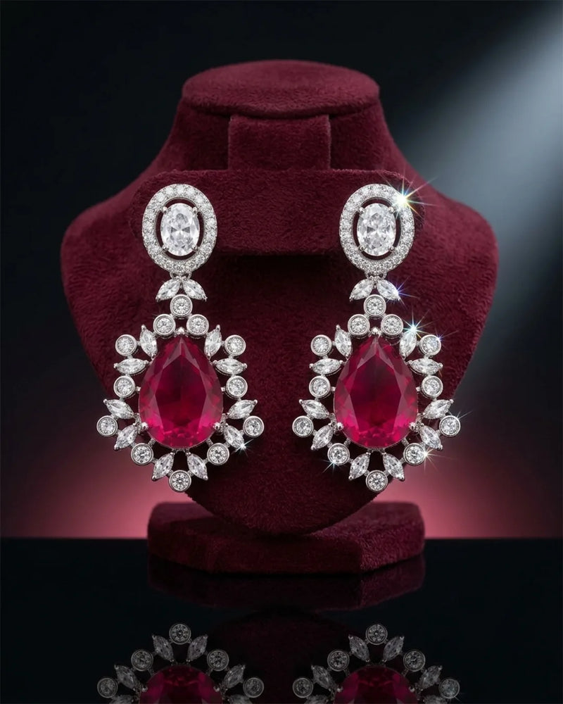 Pair of earrings with red gemstones and diamond-like accents on a dark background