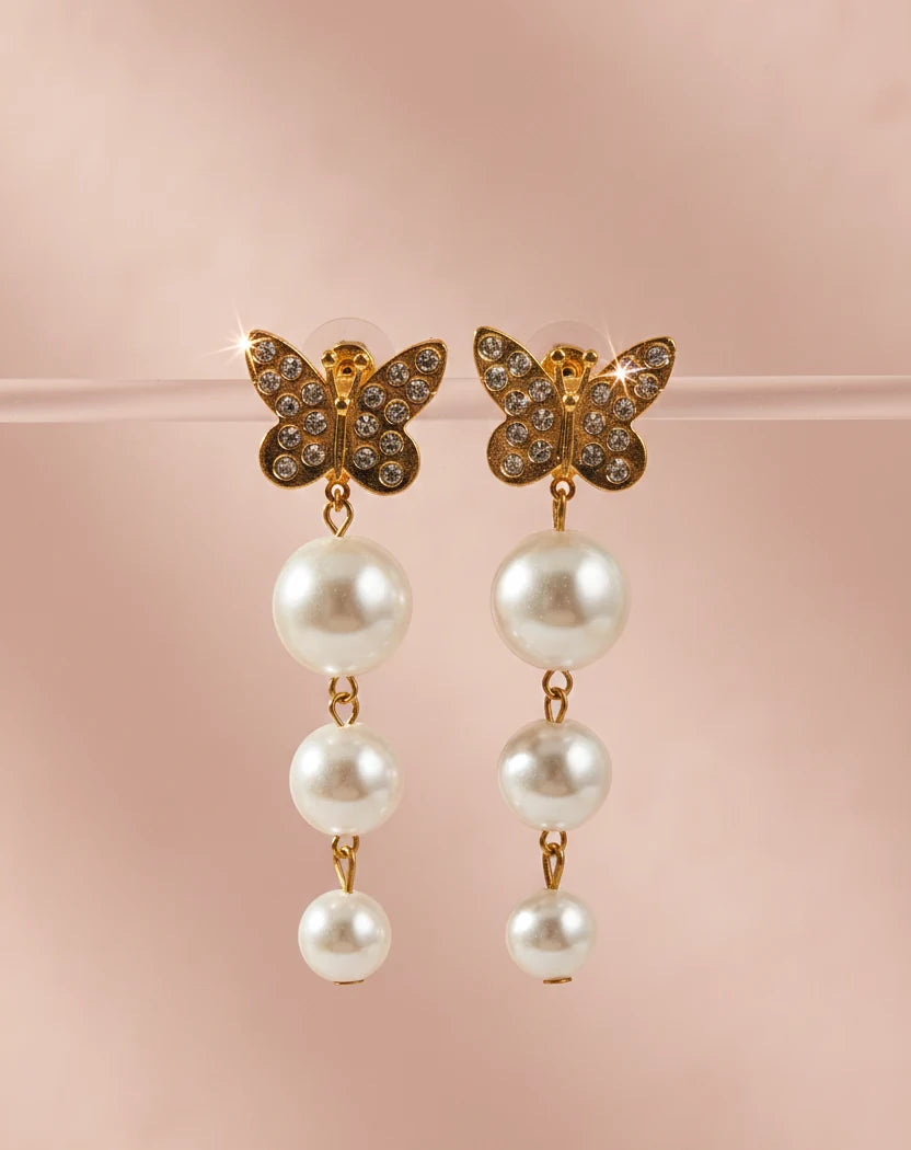 Butterfly earrings with pearl drops on a pink background
