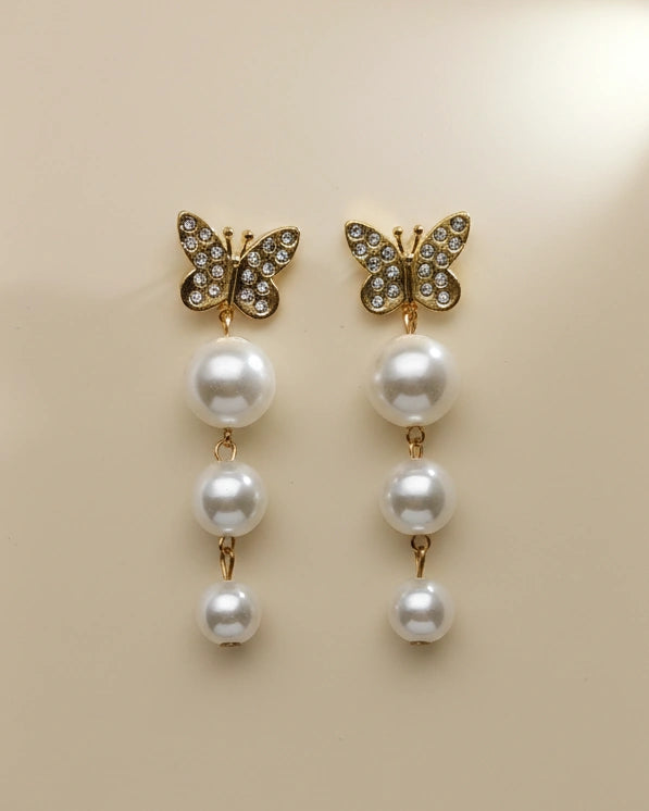 Butterfly earrings with pearl drops on a beige background