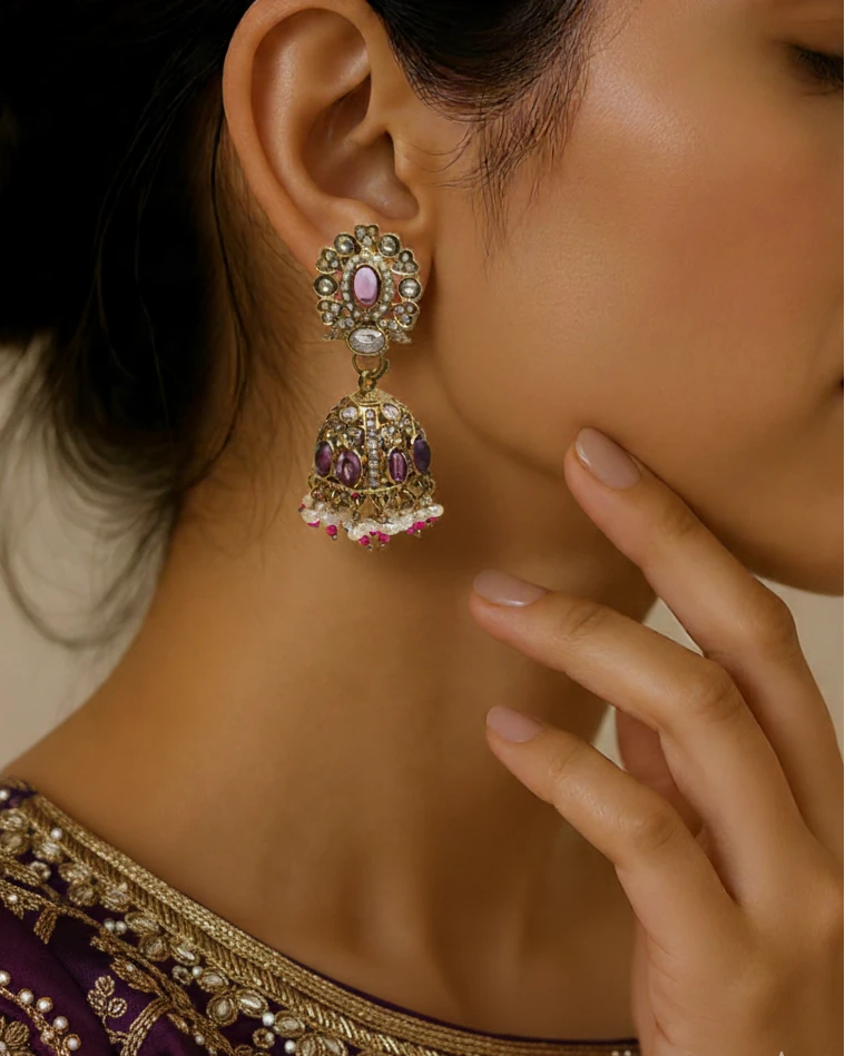 Close-up of a woman wearing ornate earrings with a hand touching her face.