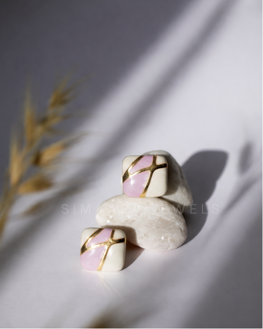 Stack of white stones with pink and gold patterns on a light background
