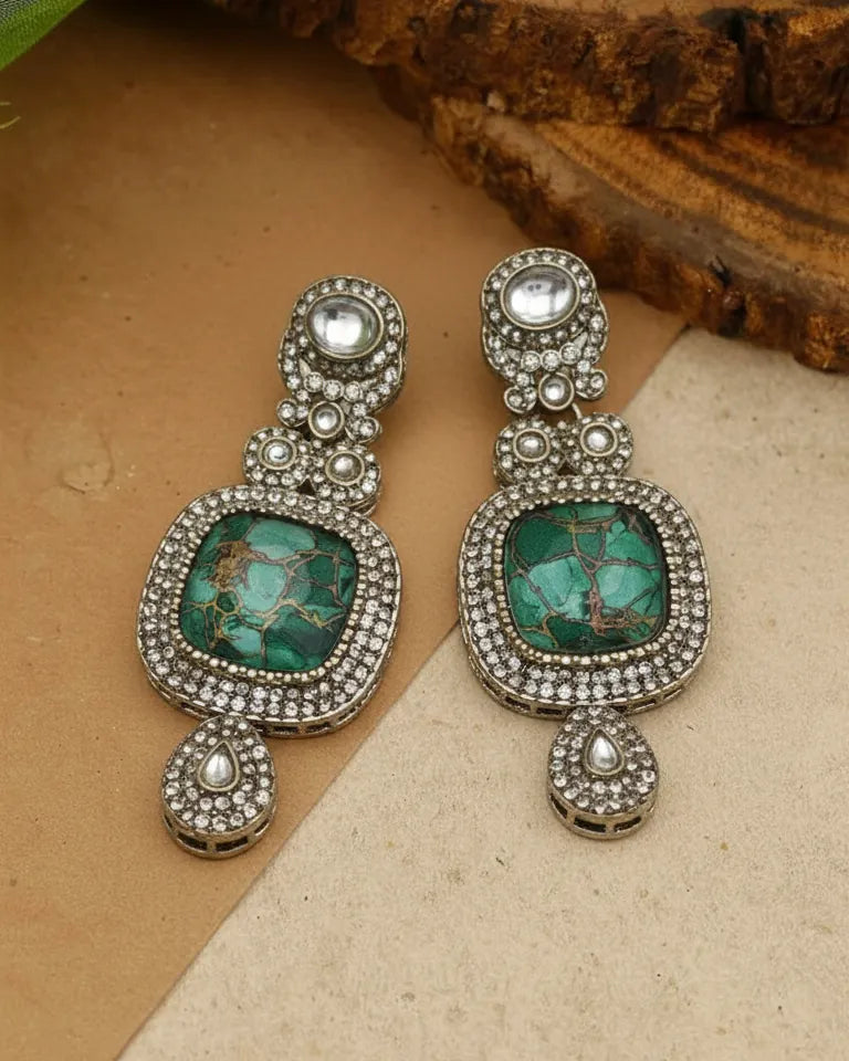 Pair of earrings with turquoise stones and silver accents on a textured surface