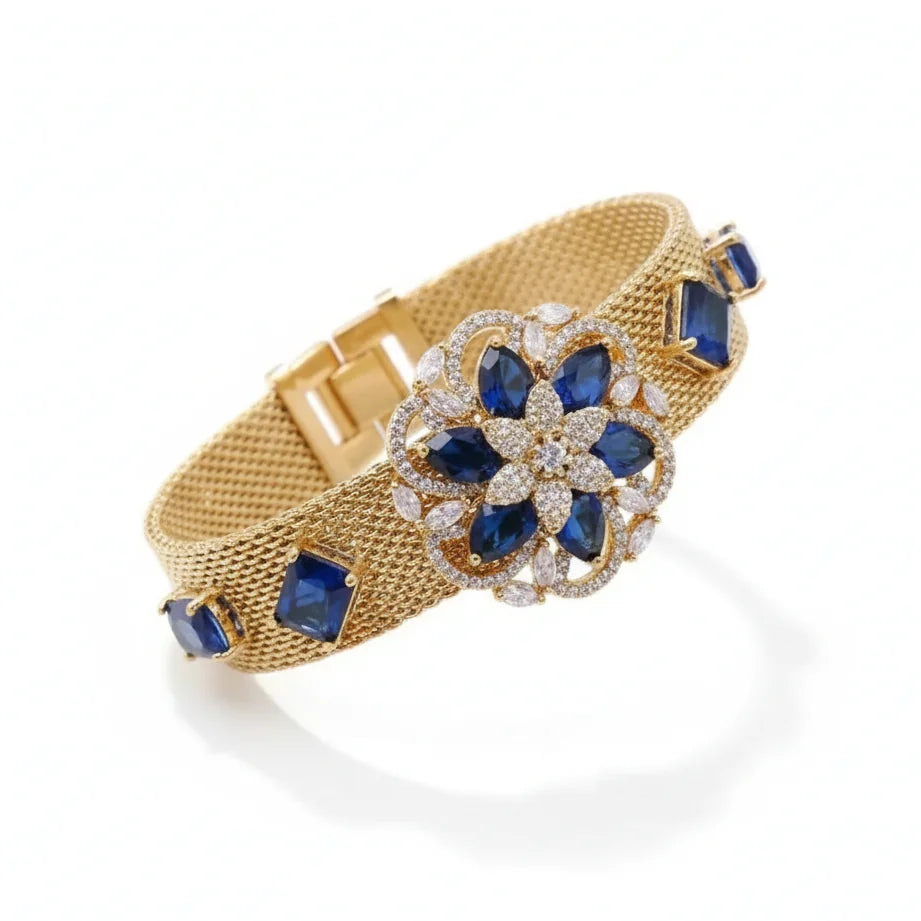 Gold bracelet with blue gemstones and diamond accents on a white background