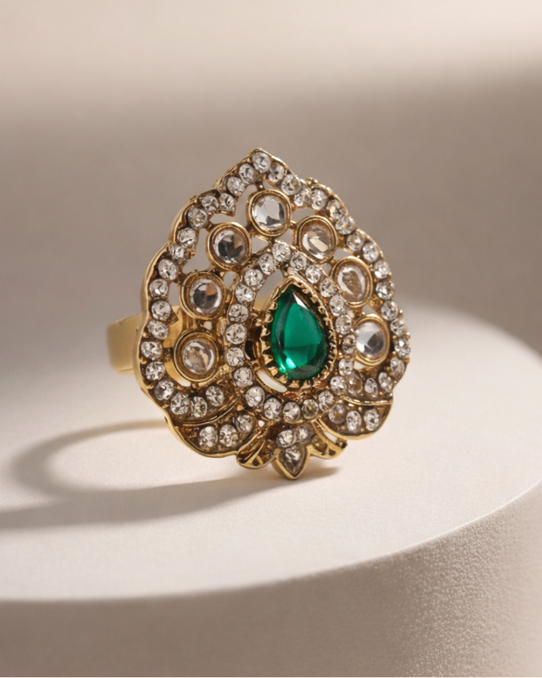 Gold ring with green gemstone on a beige background