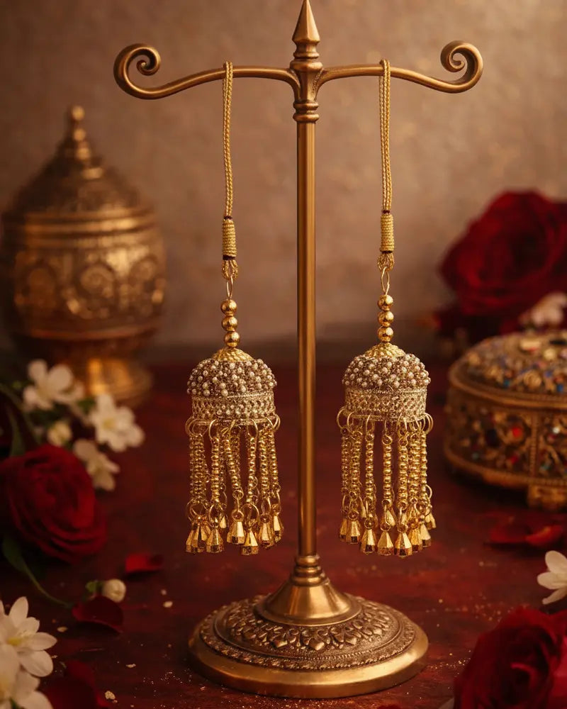 Gold earrings on a decorative stand with a floral and ornate background