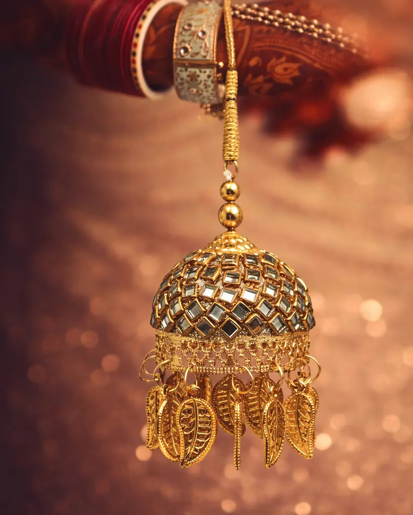 Gold jhumka earring on a blurred background