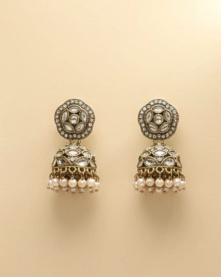 Pair of ornate earrings with pearl-like beads on a beige background