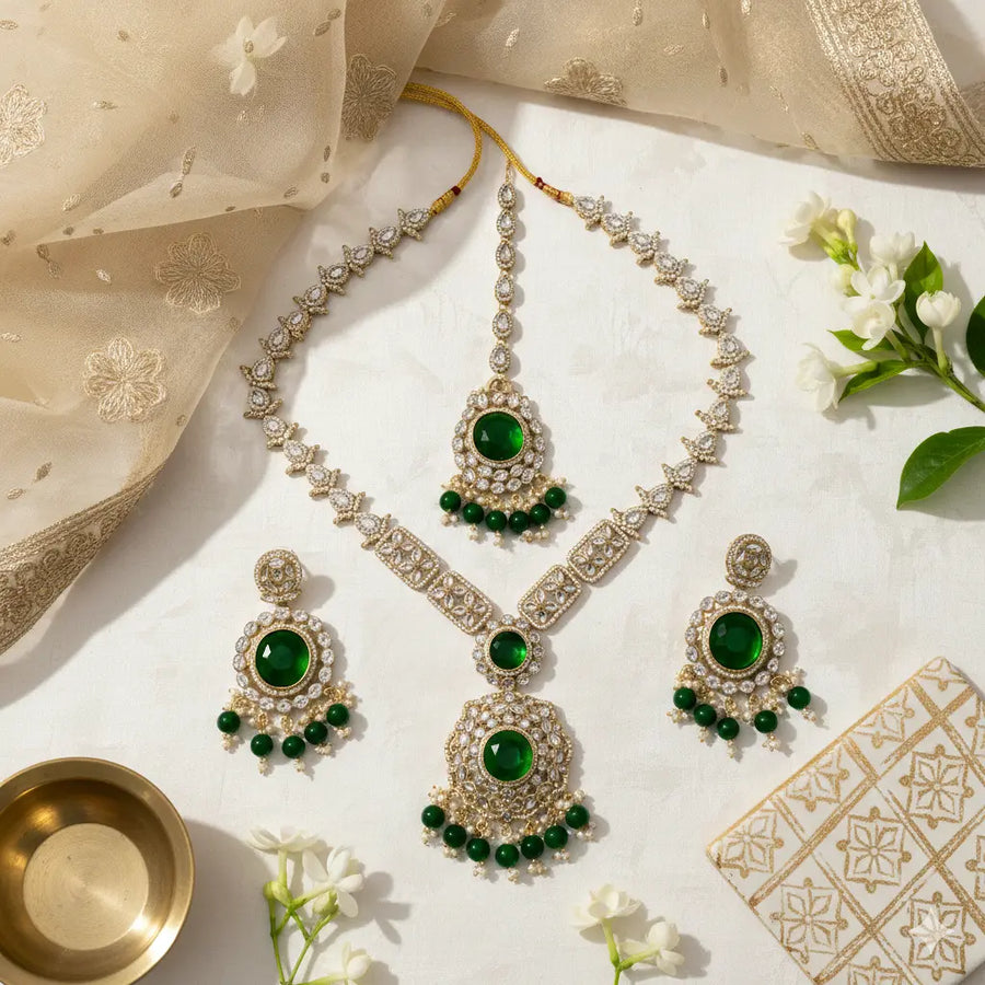 Ornate necklace and earrings with green gemstones on a decorative fabric background