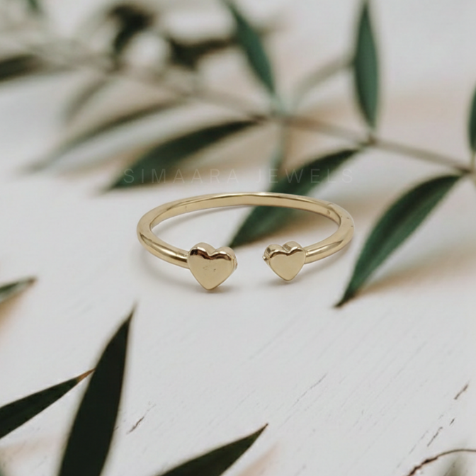 Gold ring with heart-shaped ends on a light background with leaves