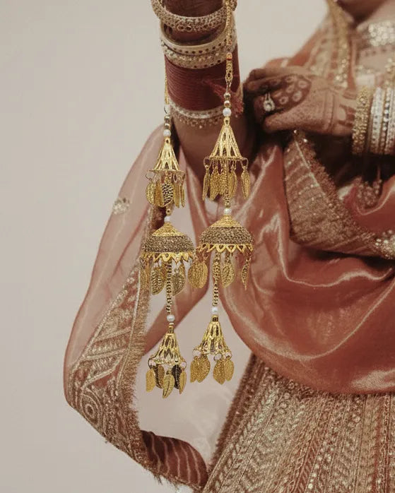 Gold earrings on a hand with traditional attire