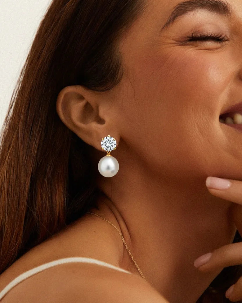 Close-up of a woman wearing pearl earrings with a neutral background
