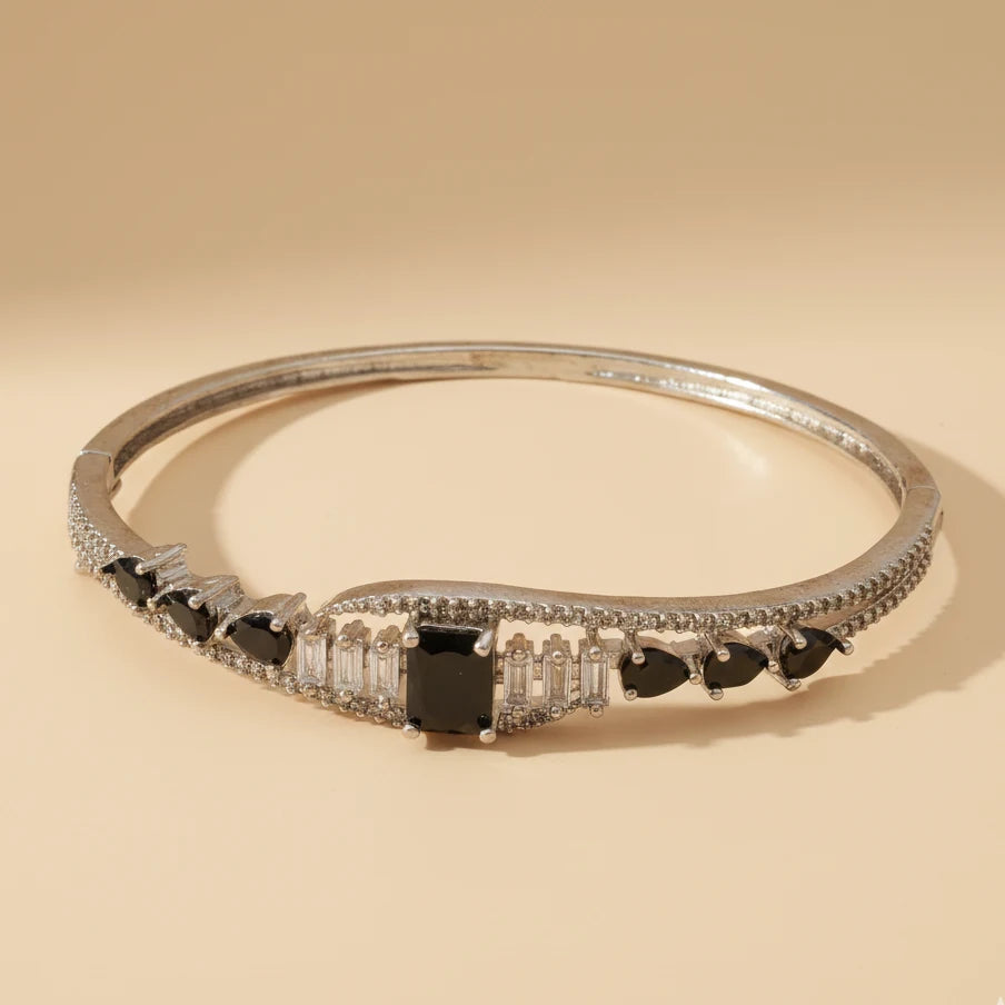 Silver bracelet with black and clear gemstones on a beige background