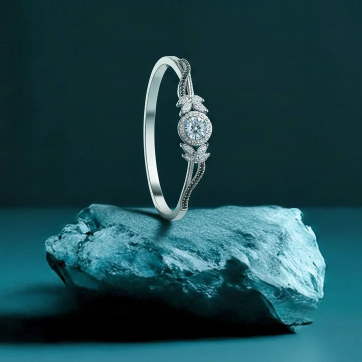 Silver ring with gemstone on a rock against a dark background