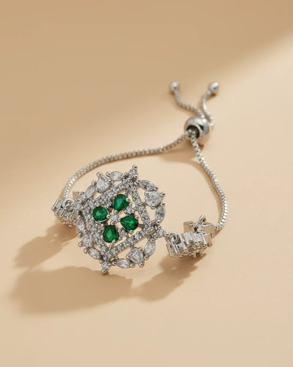 Silver bracelet with emerald and diamond accents on a beige background