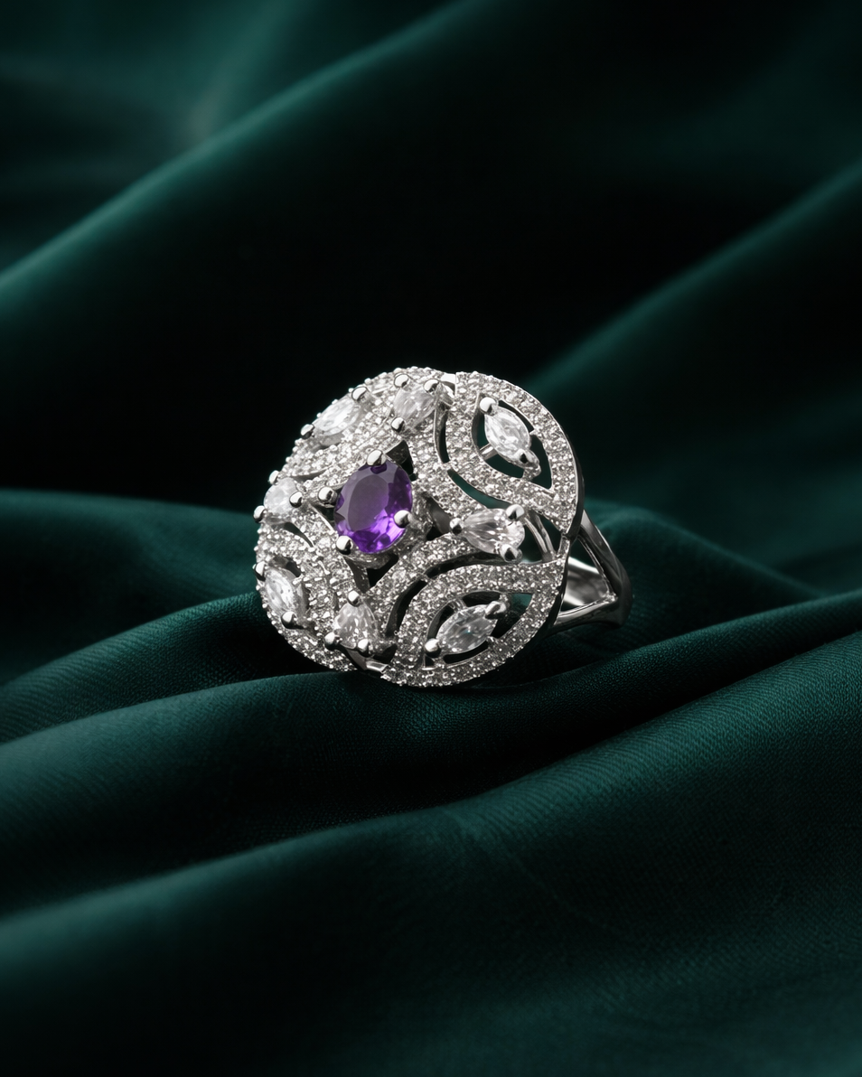 Silver ring with a purple gemstone on a dark green fabric background