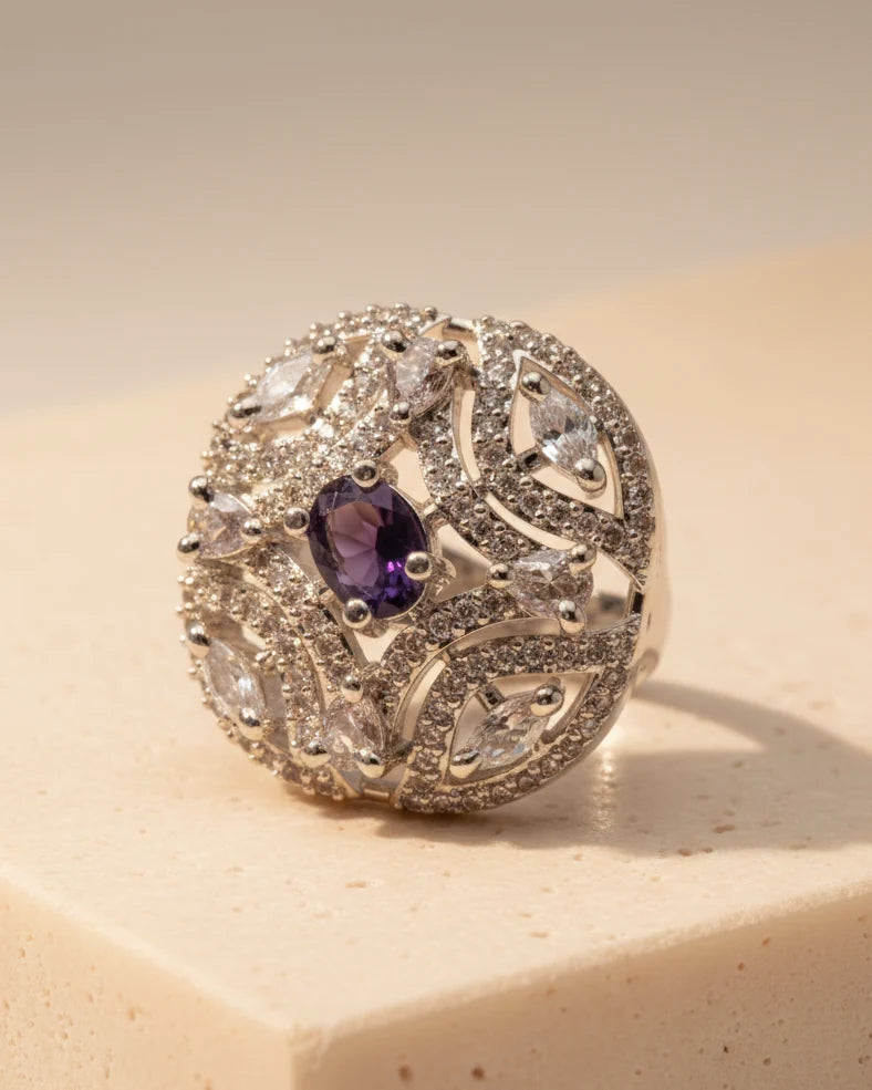 Silver ring with a purple gemstone on a beige surface