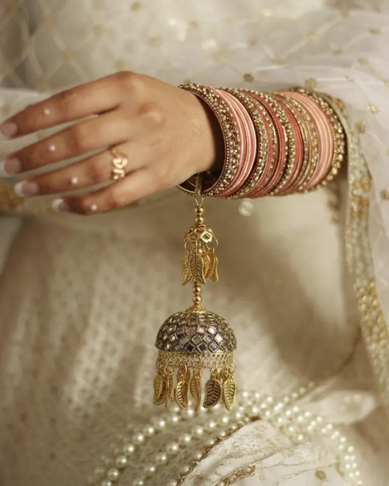 Close-up of a hand wearing multiple bangles with a decorative gold earring.