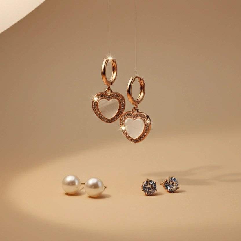 Gold heart-shaped earrings with hanging loops on a beige background