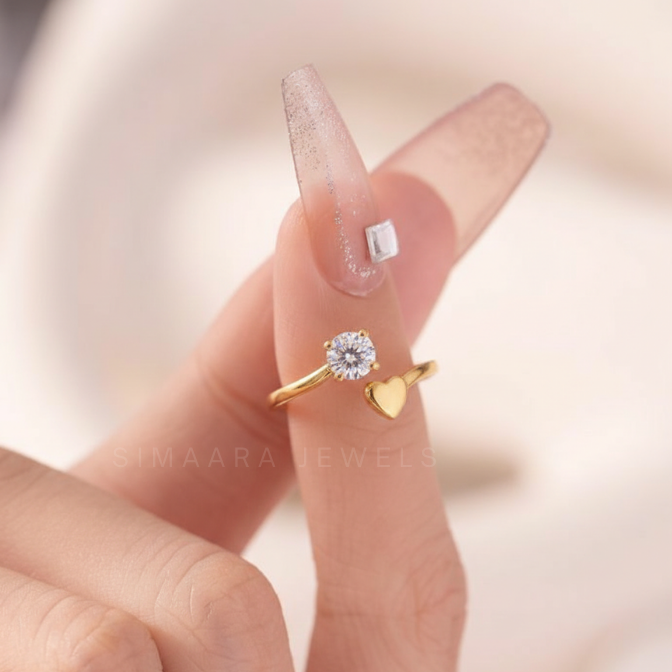 Gold ring with heart design on a finger against a blurred background