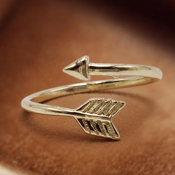 Golden arrow-shaped bracelet on a brown leather surface