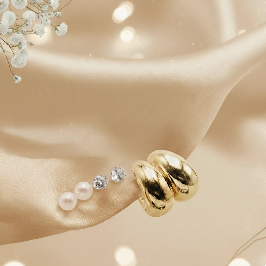 Gold earring with pearls and crystals on a beige surface with flowers.