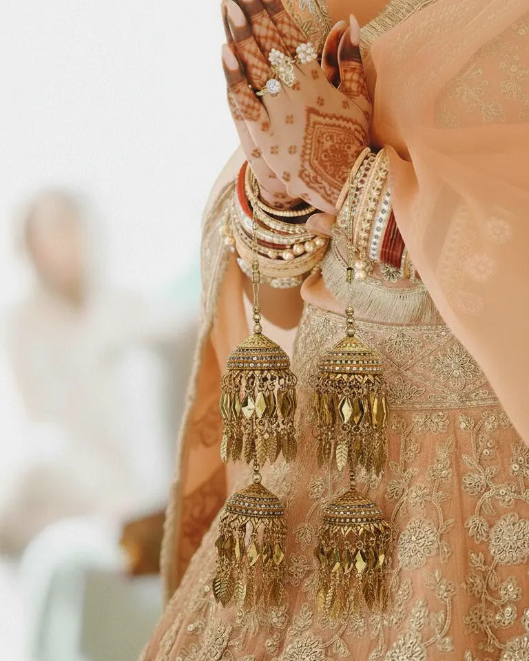 Close-up of a hand wearing gold earrings and bangles with a blurred background