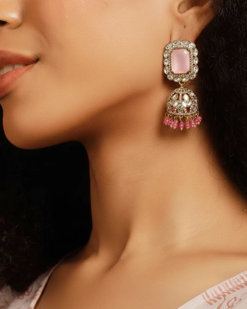 Close-up of a woman wearing a pink gemstone earring with intricate design.