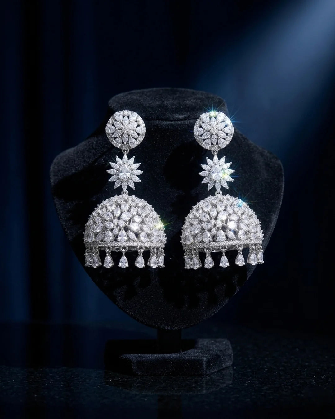 Pair of silver earrings on a black stand with a dark background