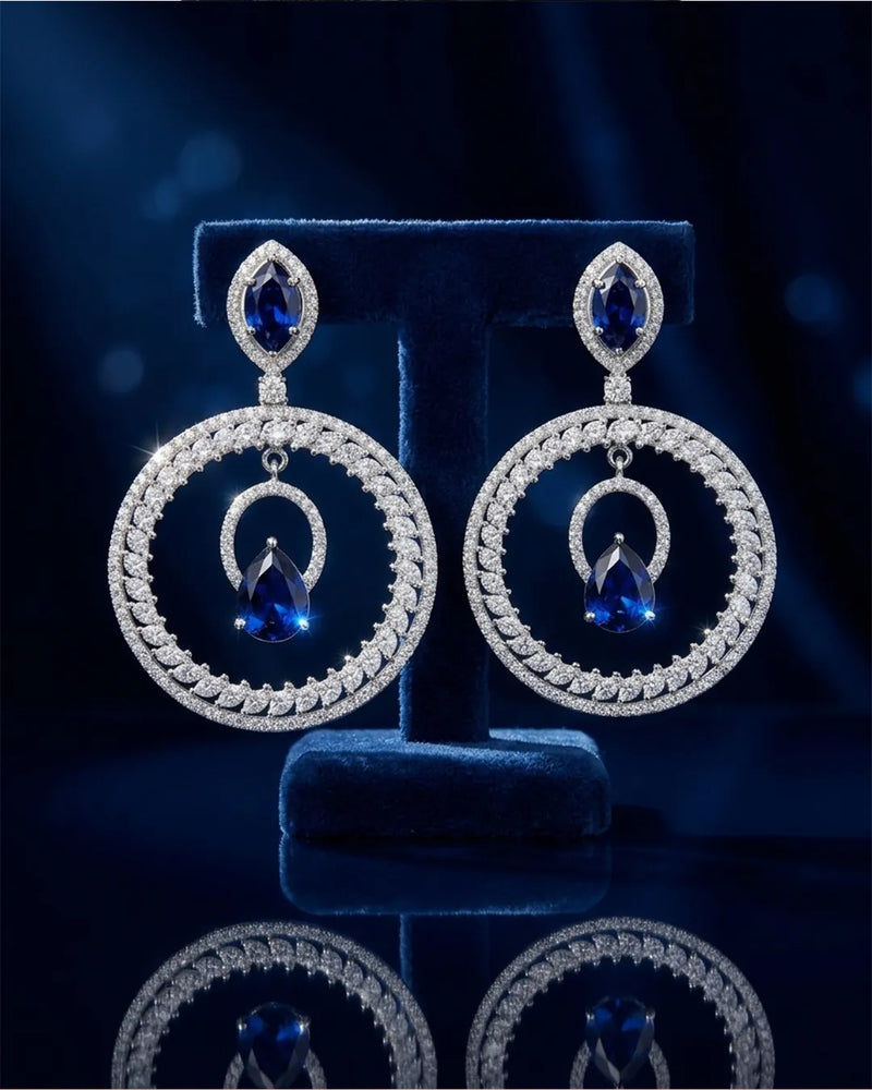 Pair of silver earrings with blue gemstones on a dark background