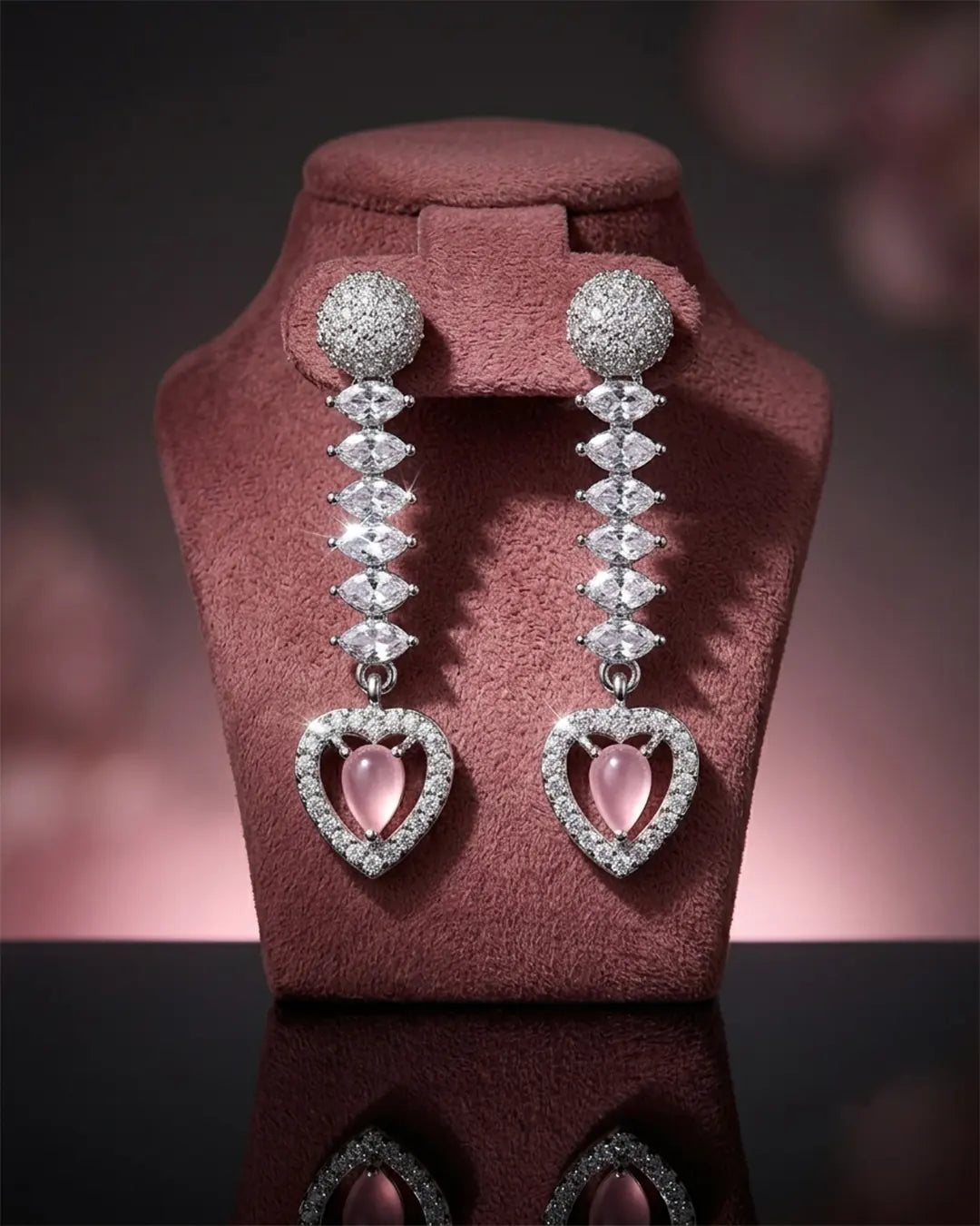 Diamond earrings with heart-shaped pink gemstones on a pink stand against a blurred background