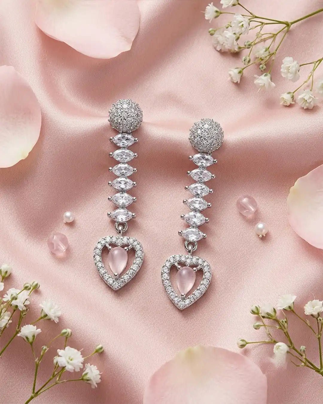 Diamond earrings with heart-shaped pink gemstones on a soft pink background with flowers.