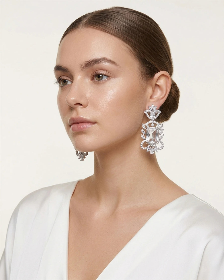 Woman wearing elegant diamond earrings against a neutral background