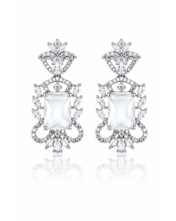 Pair of ornate earrings with clear gemstones on a white background