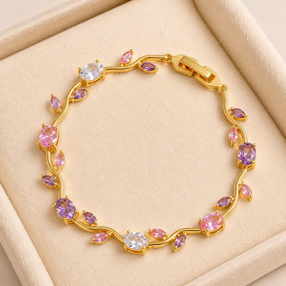 Gold bracelet with pink and purple gemstones on a beige background