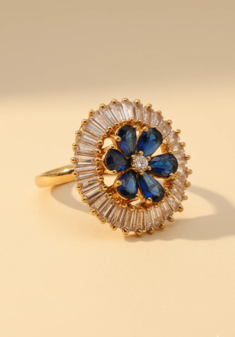 Golden ring with blue gemstones and clear stones on a beige background