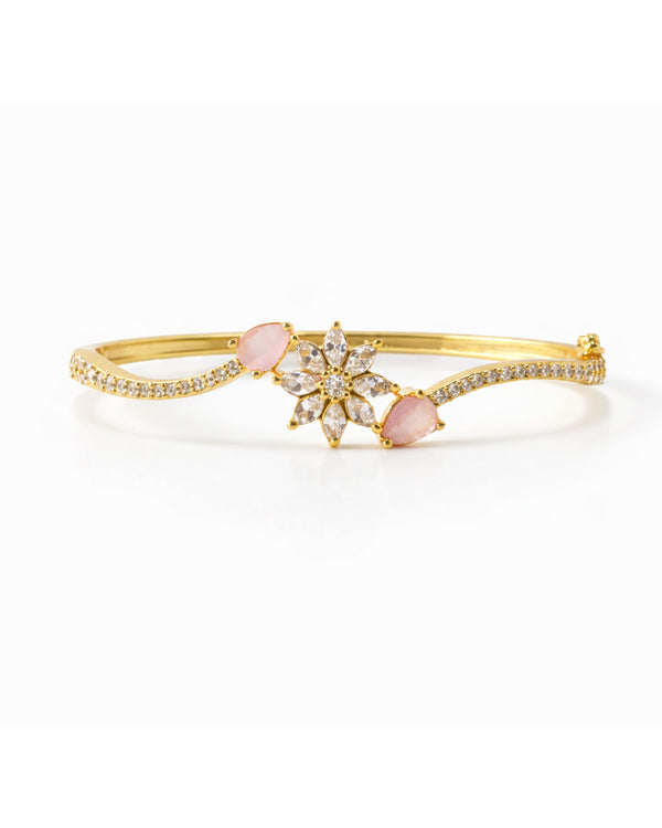 Gold bracelet with pink gemstone on a white background