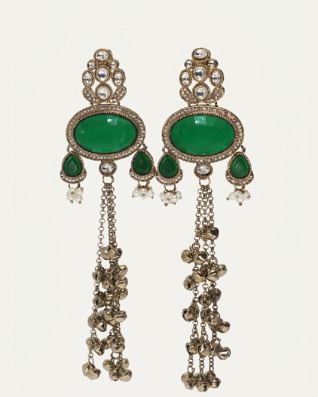 Pair of ornate earrings with green gemstones and dangling elements on a white background