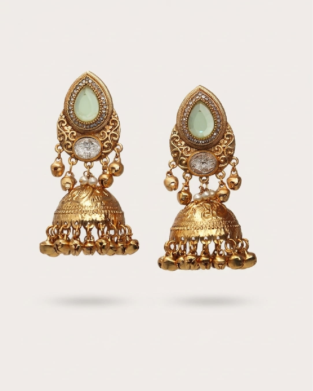 Gold earrings with green gemstones on a light gray background