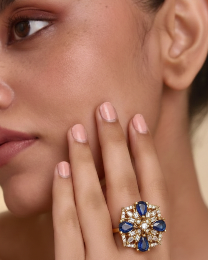 Close-up of a woman's face wearing a ring with blue gemstones and gold accents.