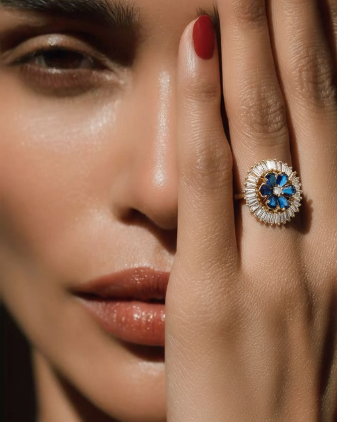 Close-up of a woman's face with a ring on her finger featuring a blue gemstone.