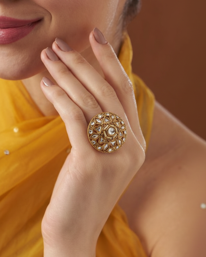 Close-up of a hand wearing an ornate gold ring with a blurred background