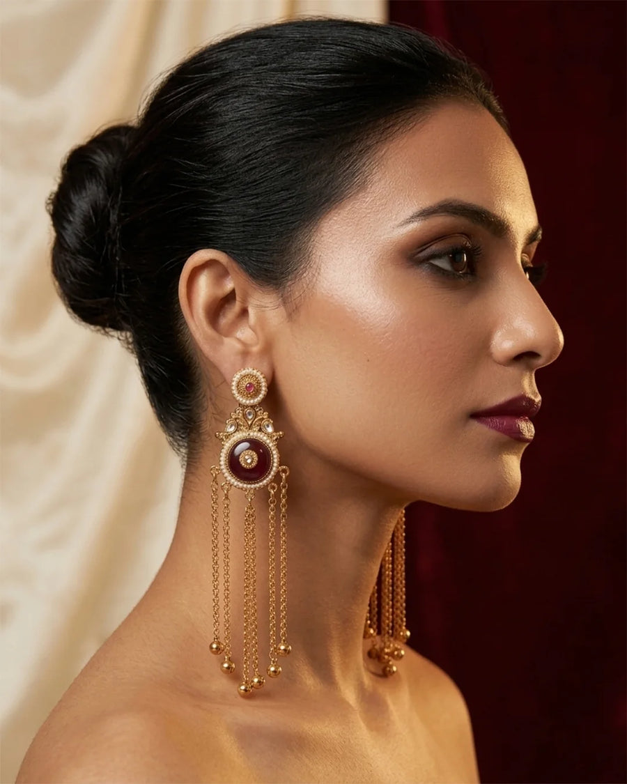 Woman wearing gold earrings with a dark background