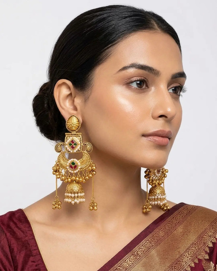 Woman wearing gold earrings with a plain background