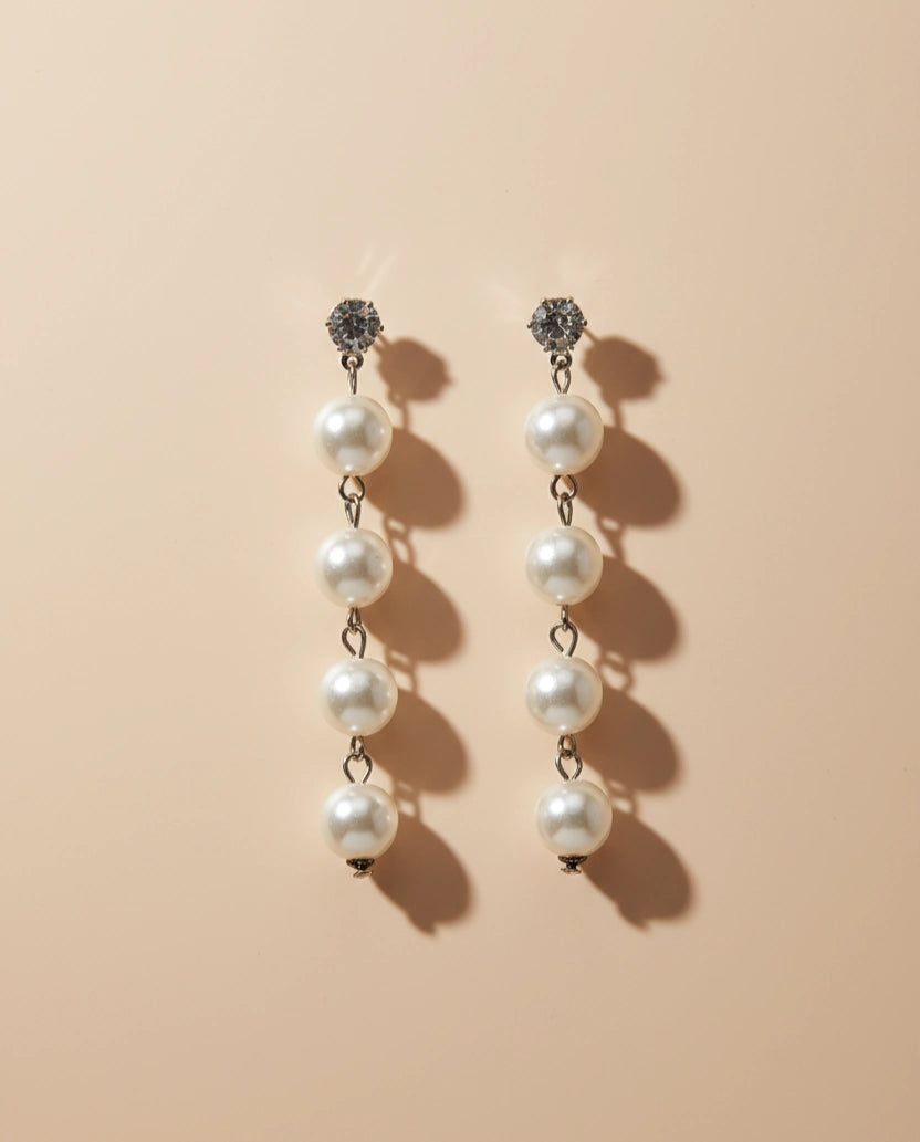 Pair of pearl earrings on a beige background