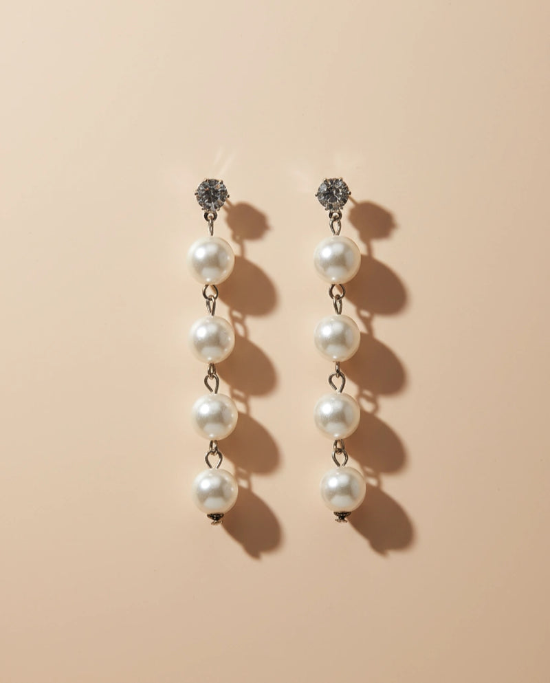 Pair of pearl earrings on a beige background