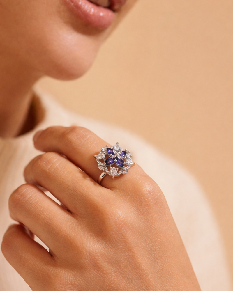 Close-up of a hand wearing a decorative ring with gemstones on a beige background