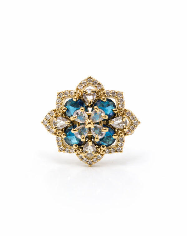 Gold and blue gemstone brooch on a white background