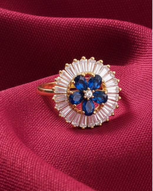 Ring with blue gemstone and gold accents on a red fabric background
