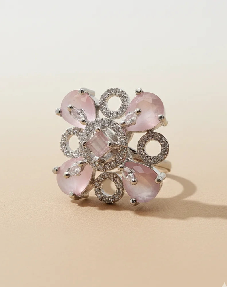 Elegant ring with pink gemstones and silver accents on a beige background