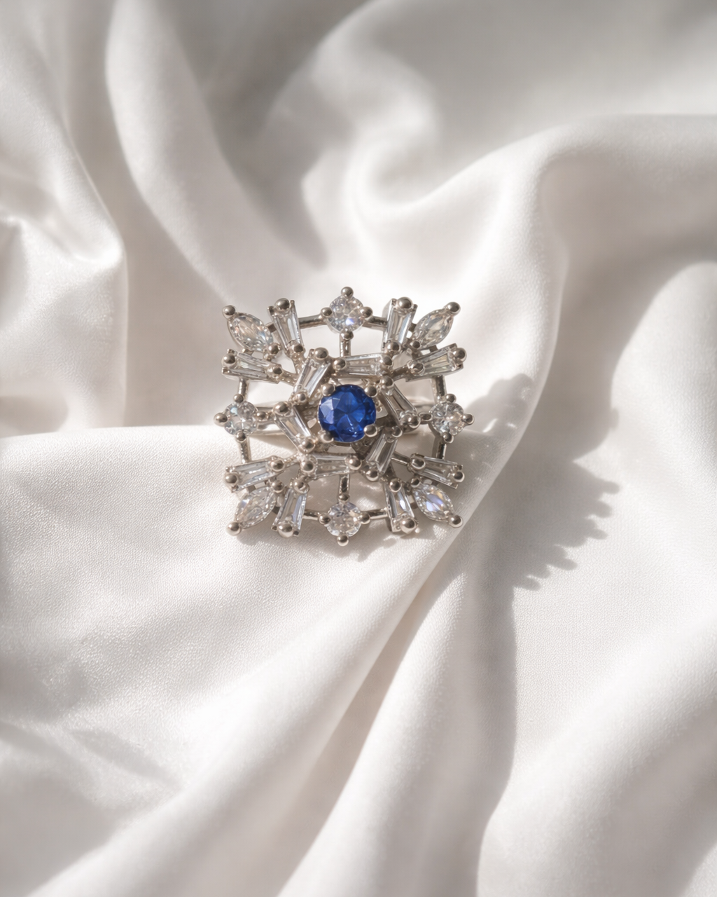 Diamond brooch with a blue gemstone on white fabric